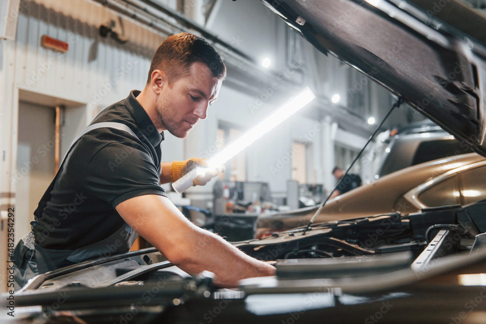 Ready to solve the problem. Man in uniform is working in the auto service Ready to solve the problem. Man in uniform is working in the auto service