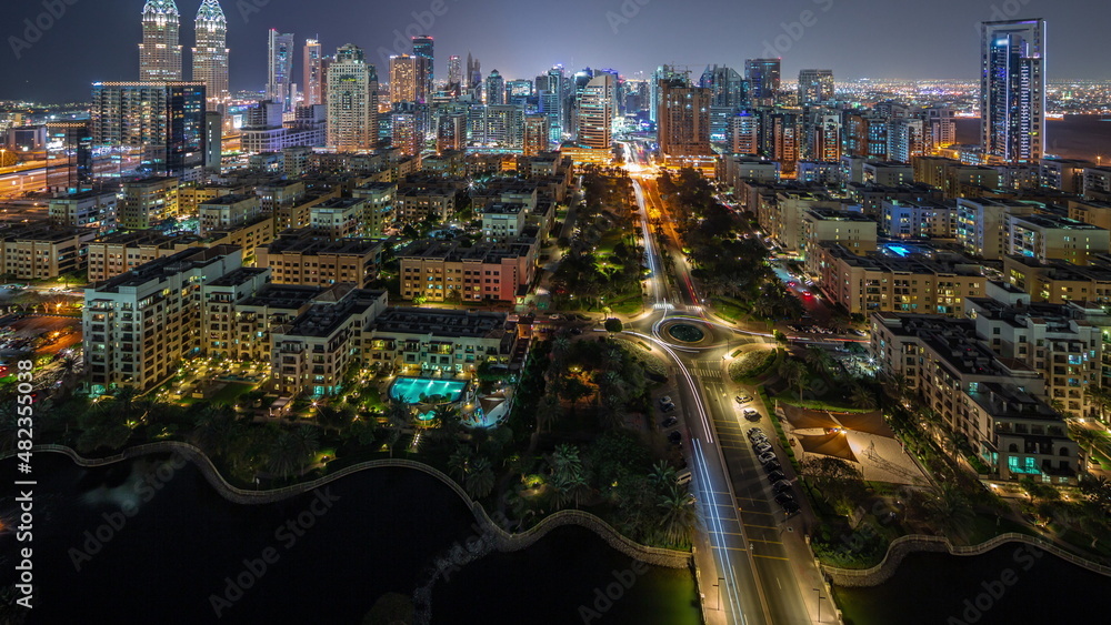 Obraz premium Skyscrapers in Barsha Heights district and low rise buildings in Greens district aerial night timelapse.