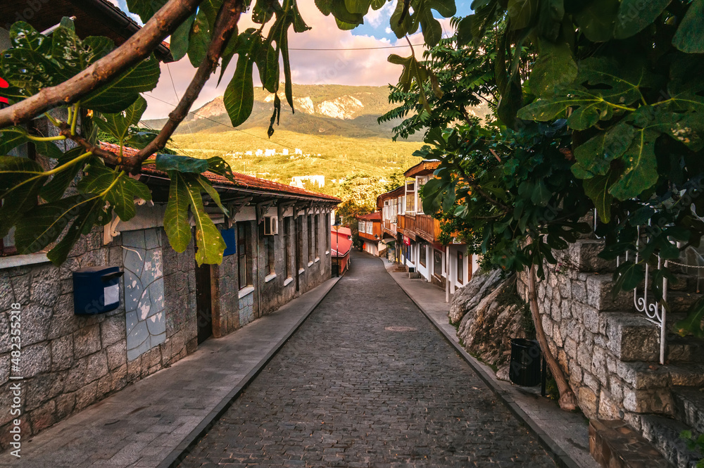 beautiful street with stone historical houses and paving stones against the backdrop of mountains in the resort of Gurzuf in the Crimea beautiful street with stone historical houses and paving stones against the backdrop of mountains in the resort of Gurzuf in the Crimea