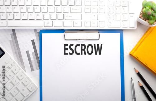 ESCROW written on the paper with keyboard, chart, calculator and notebook