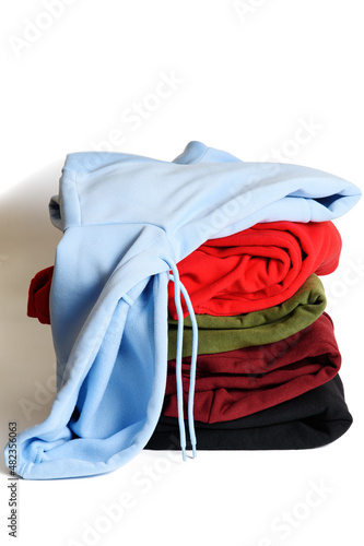 Obraz na płótnie Folded hoodies and hooded sweatshirts on white background. Light blue hoodie on top of stack. Trendy comfortable casual clothes. Closeup. Vertical orientation. w salonie
