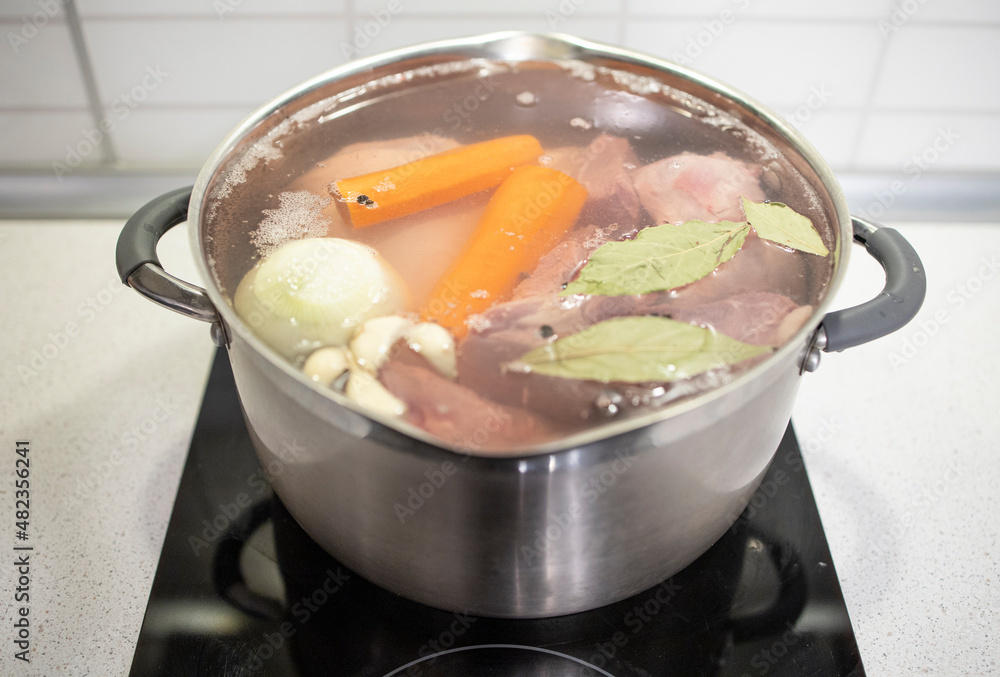cooking at home, vegetables, meat, bay leaf are boiled in a pot at home. Homemade, meat broth, natural collagen cooking at home, vegetables, meat, bay leaf are boiled in a pot at home. Homemade, meat broth, natural collagen