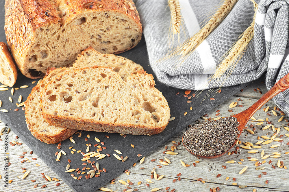 Freshly baked traditional sliced rye bread on black board. Whole grain rye bread with seeds and spikelets.