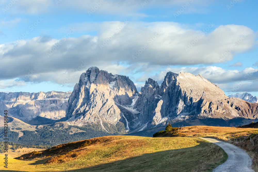 Scenic trail on the plateau in Seiser Alm leading to the mountains Sassolungo and Sassopiatto. South Tyrol, Italy. Scenic trail on the plateau in Seiser Alm leading to the mountains Sassolungo and Sassopiatto. South Tyrol, Italy.
