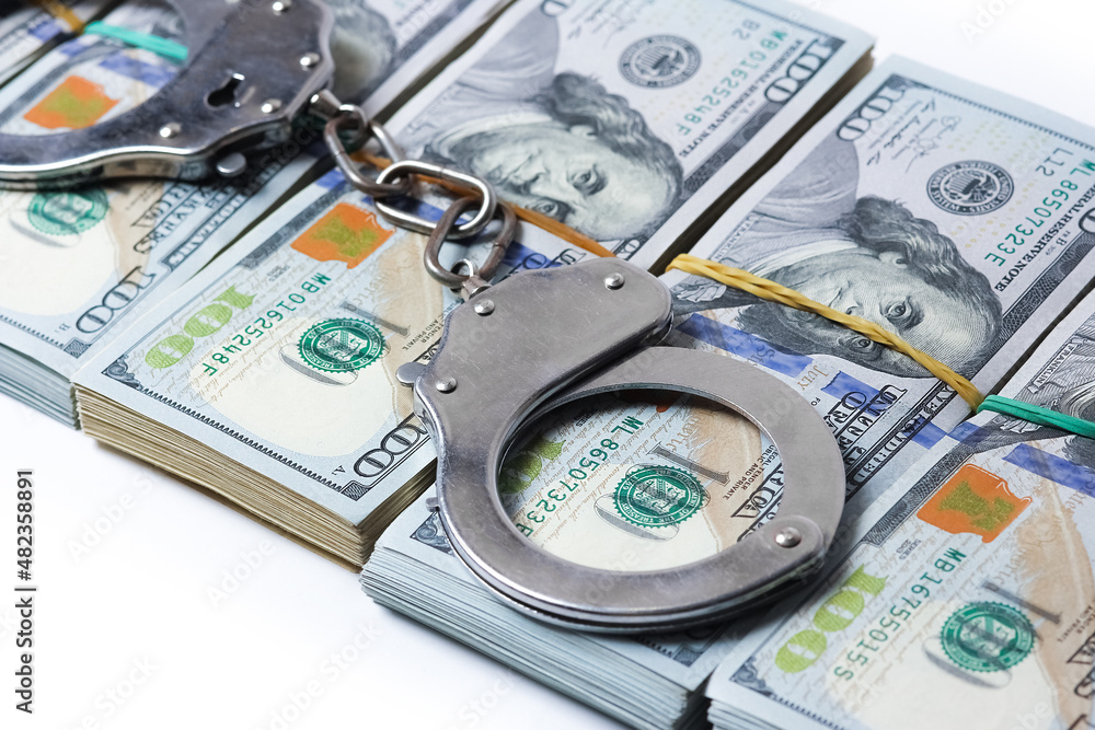 A dollars in bundles on white background with handcuffs crime fraud concept business pandemic A dollars in bundles on white background with handcuffs crime fraud concept business pandemic