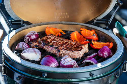 outdoor grilling a staek with onions on a ceramic grill with charcoal at a winter day photo