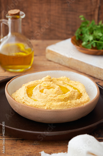 Homemade hummus with bread sticks and parsley on wooden background copy space. Selective focus.