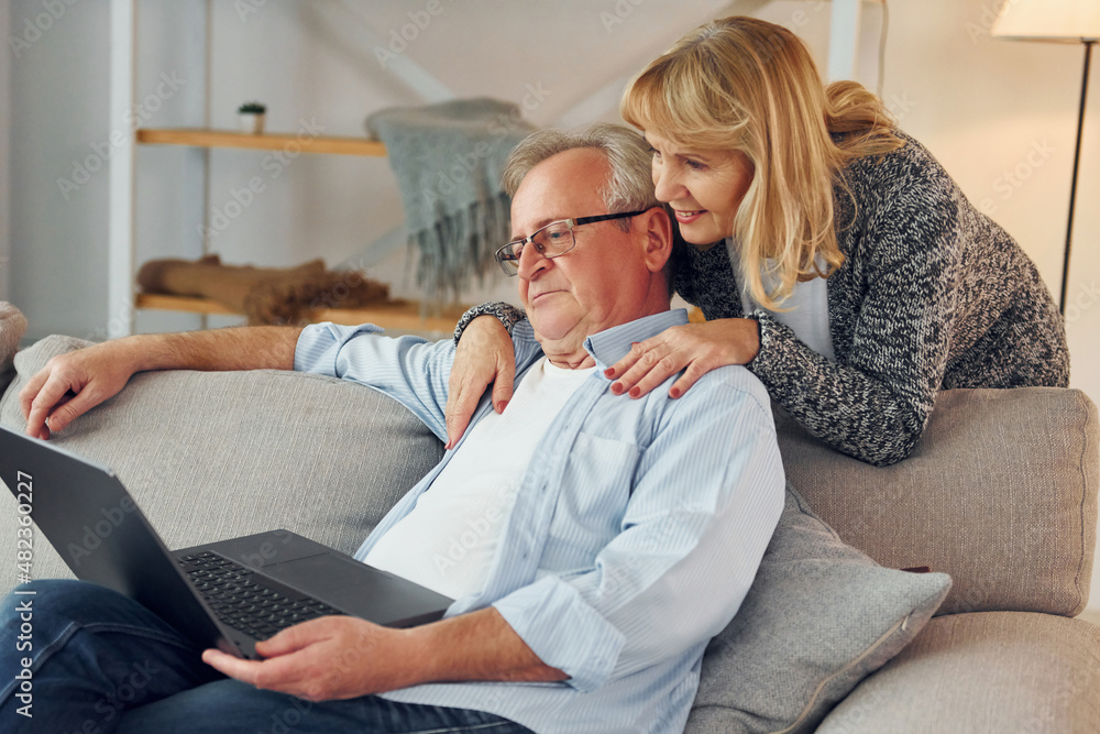 With modern laptop. Senior man and woman is together at home With modern laptop. Senior man and woman is together at home