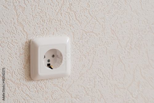 A white socket on the wall. Electricity equipment in interior. © Valentina