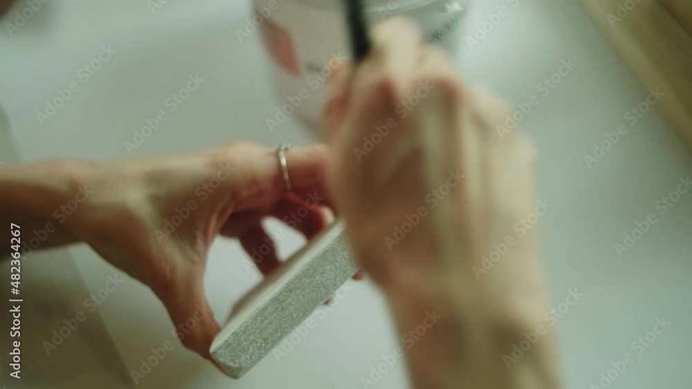 A woman paints a wooden part of a wooden product with a brush. Business idea for a home workshop A woman paints a wooden part of a wooden product with a brush. Business idea for a home workshop