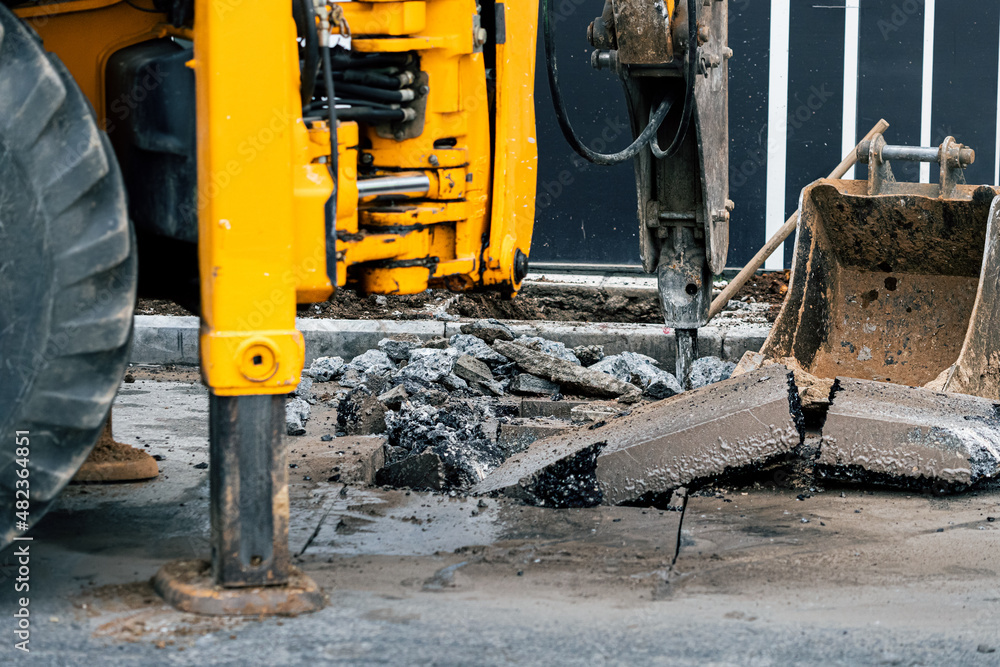 Heavy machinery removes the old layer of asphalt on a city street with a pneumatic jackhammer. Dangerous road construction work and decibel rumbling Heavy machinery removes the old layer of asphalt on a city street with a pneumatic jackhammer. Dangerous road construction work and decibel rumbling