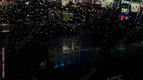 Rainy night in the parking lot of shops with colorful signs of light