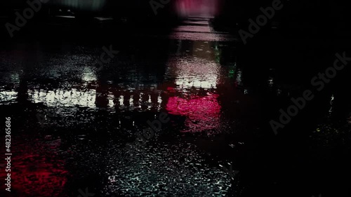 On a rainy night, water drops on asphalt. Reflection of a neons signs