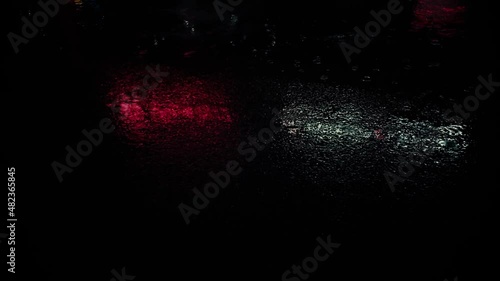 On a rainy night, water drops on asphalt. Reflection of a neons signs
