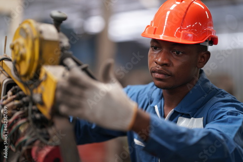 Portrait of Professional Heavy Industry Engineer / Worker Wearing Safety Uniform, Goggles and Hard Hat. In the Background Unfocused Large Industrial Factory