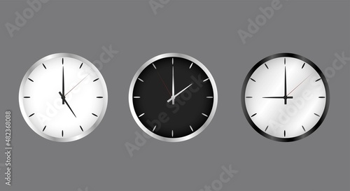 Realistic clock on the wall, black and white. The arrow on the dial shows the time. The set is dark and light. Metal, silver edging.
Vector image.