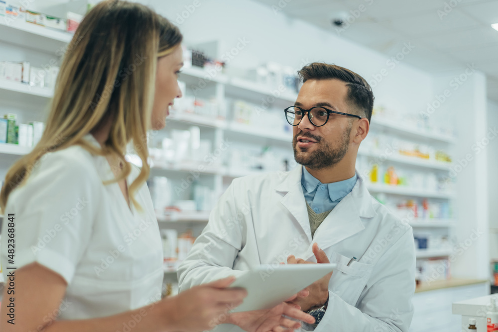 Male pharmacist working with young female colleague in a pharmacy Male pharmacist working with young female colleague in a pharmacy