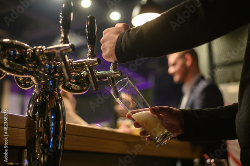 Hand of bartender using beer tap while working in a bar