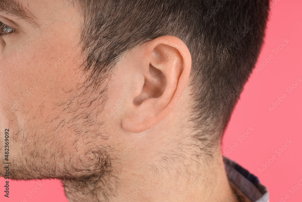 Fototapeta premium Young man's head on pink background, hearing problem concept