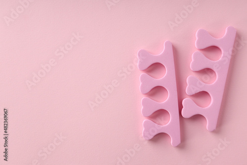 Pink nail separators on pink background, close up © Atlas