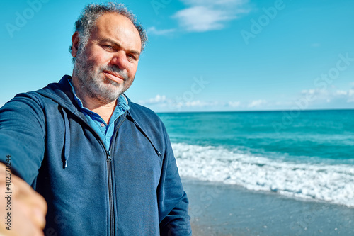 Happy, smiling mature bearded man making a selfie on seaside background. Concept of leisure activities,tourism, lifestyle e nature.