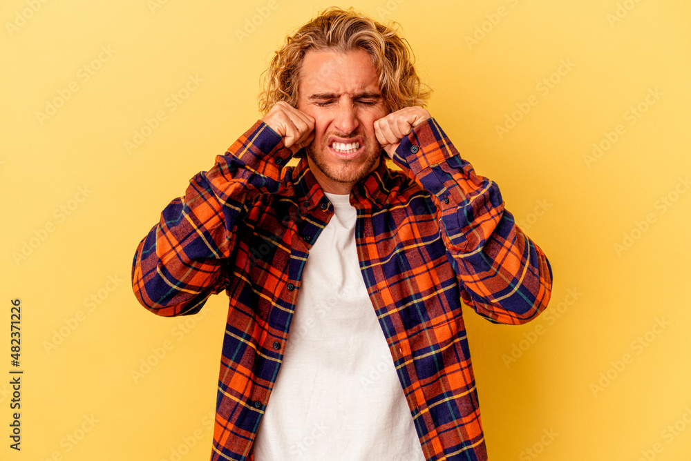 Young caucasian man isolated on yellow background whining and crying disconsolately. Young caucasian man isolated on yellow background whining and crying disconsolately.