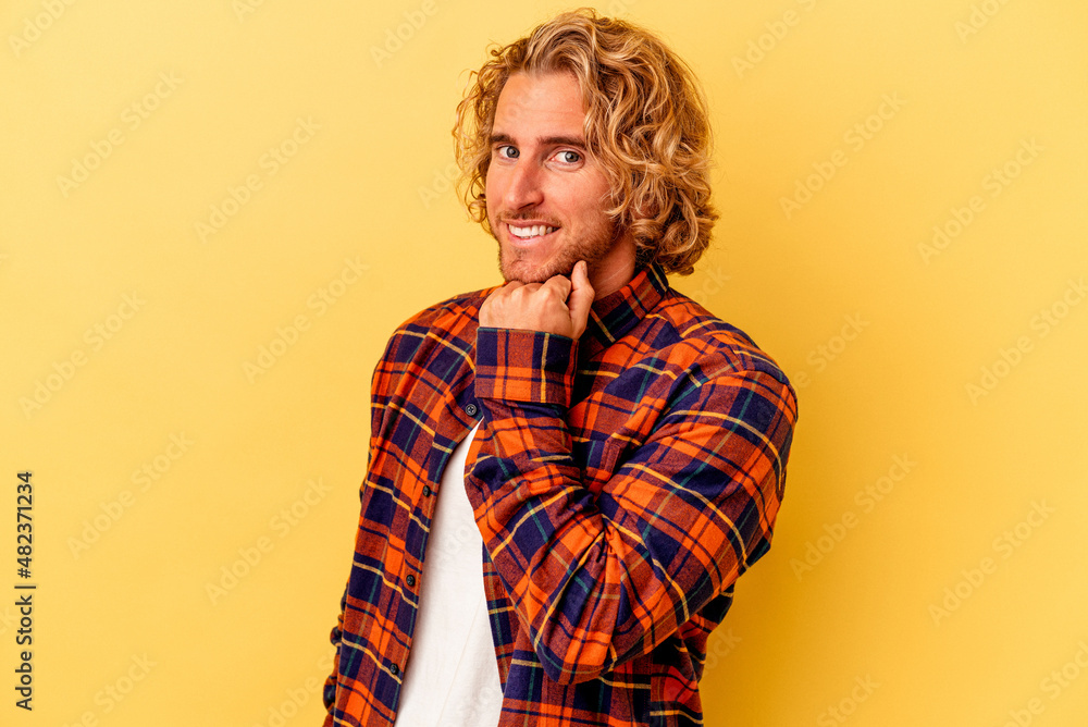 Young caucasian man isolated on yellow background smiling happy and confident, touching chin with hand. Young caucasian man isolated on yellow background smiling happy and confident, touching chin with hand.