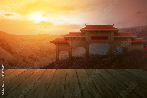 Wooden floor with a view of Chinese pavilion gate with red roof on the hill