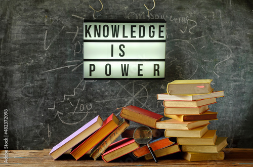 knowledge is power, education,learning,back to school concept,illuminated display, heap of books and magnifying glass