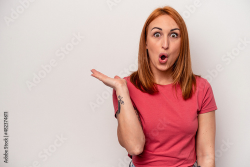 Wallpaper Mural Young caucasian woman isolated on white background impressed holding copy space on palm. Torontodigital.ca