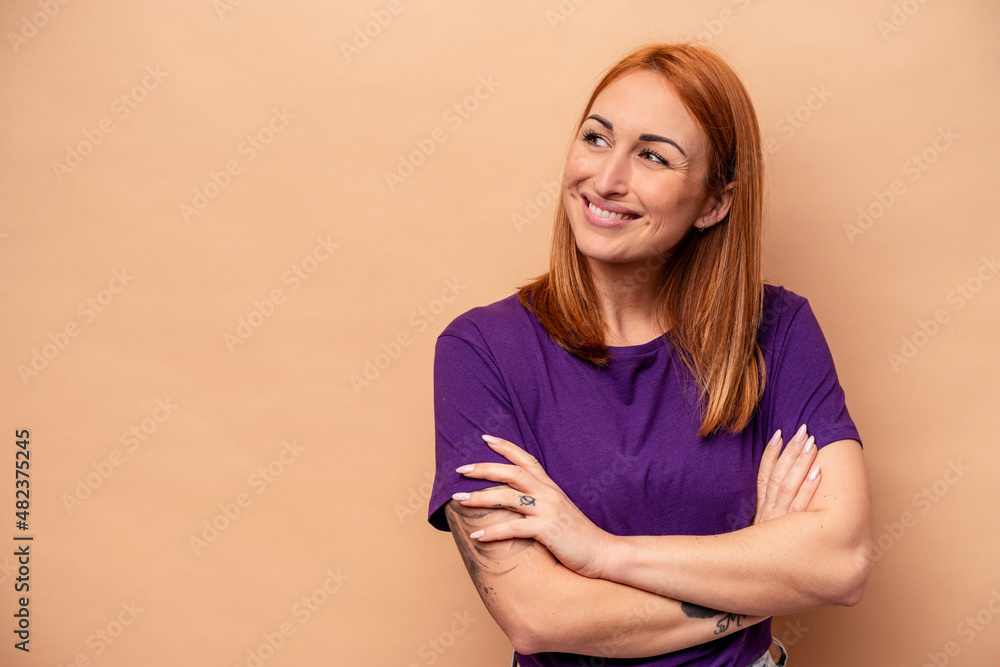Obraz premium Young caucasian woman isolated on beige background smiling confident with crossed arms.