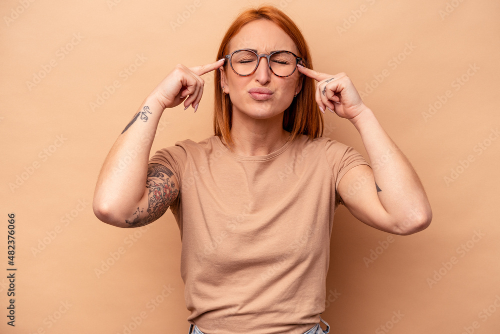 Young caucasian woman isolated on beige background focused on a task, keeping forefingers pointing head. Young caucasian woman isolated on beige background focused on a task, keeping forefingers pointing head.