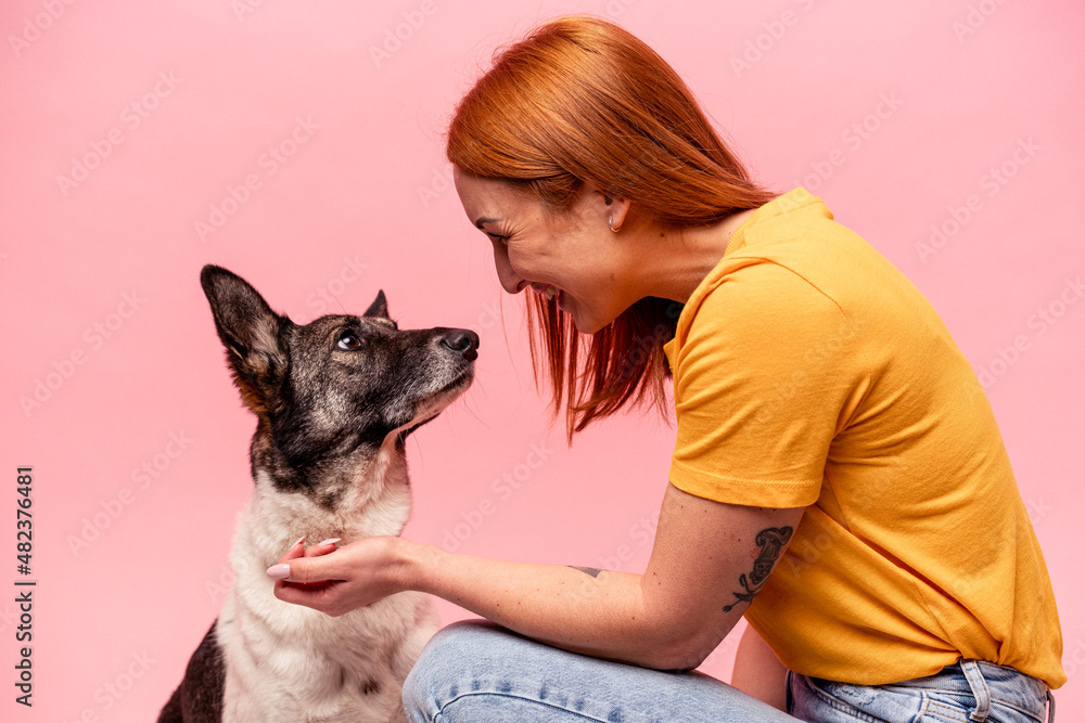 Young caucasian woman with his dog isolated on pink background Young caucasian woman with his dog isolated on pink background