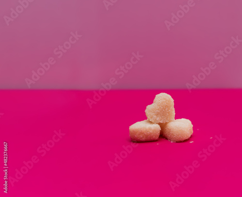 Coconut candies in the form of hearts on a pink background. Composition for Valentine's Day. Flat lay, copy space. Greeting card. Food.