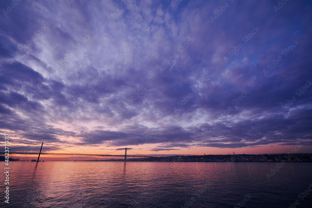 Fototapeta premium Beautiful landscape with suspension 25 April bridge bridge over the Tagus river in Lisbon at sunset.