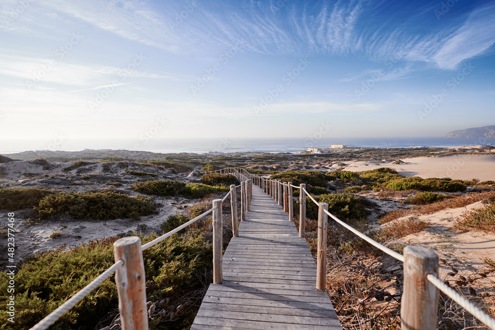 Wooden pedestrian walkway through Sintra-Cascais natural park. Wild sandy landscape, with part of Cresmina Dunes. Beautiful scenery in Portugal.