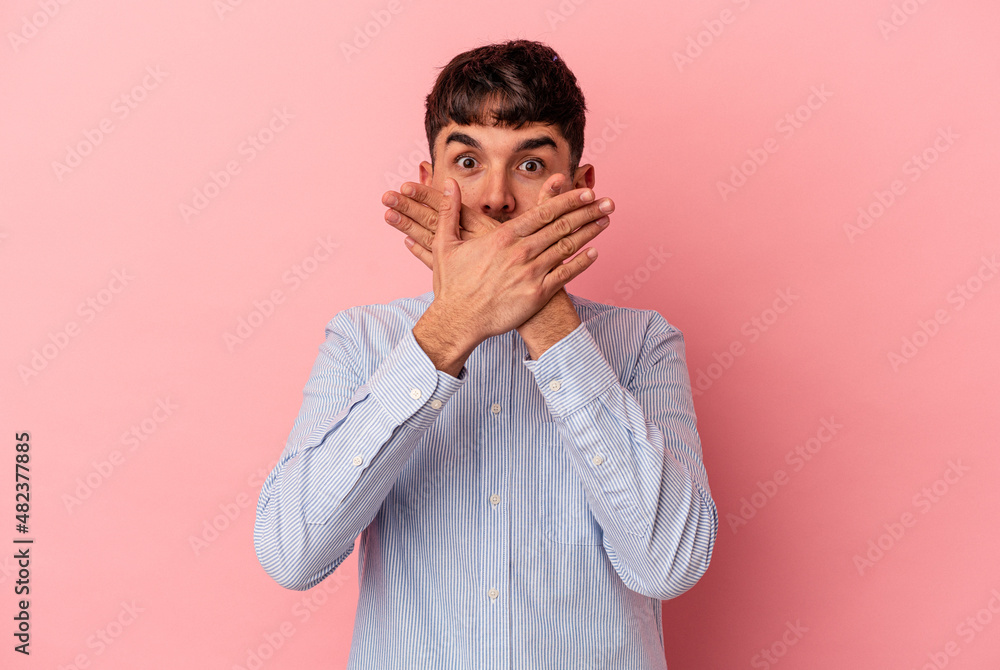 Young mixed race man isolated on pink background shocked covering mouth with hands.