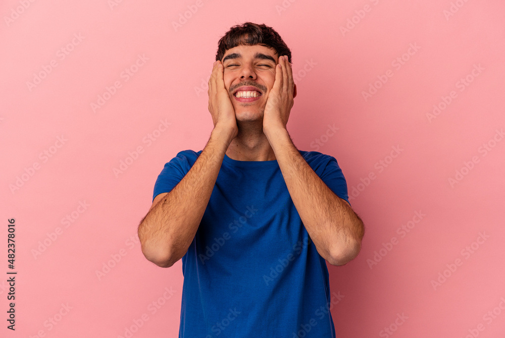 Young mixed race man isolated on pink background laughs joyfully keeping hands on head. Happiness concept. Young mixed race man isolated on pink background laughs joyfully keeping hands on head. Happiness concept.