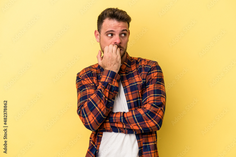 Young caucasian man isolated on yellow background biting fingernails, nervous and very anxious. Young caucasian man isolated on yellow background biting fingernails, nervous and very anxious.