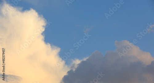 Blue sky with curly clouds and sun, sunset with sun rays.