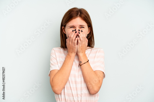 Young English woman isolated on blue background laughing about something, covering mouth with hands.