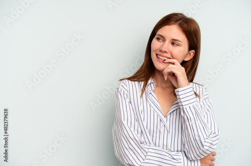Young English woman isolated on blue background relaxed thinking about something looking at a copy space.
