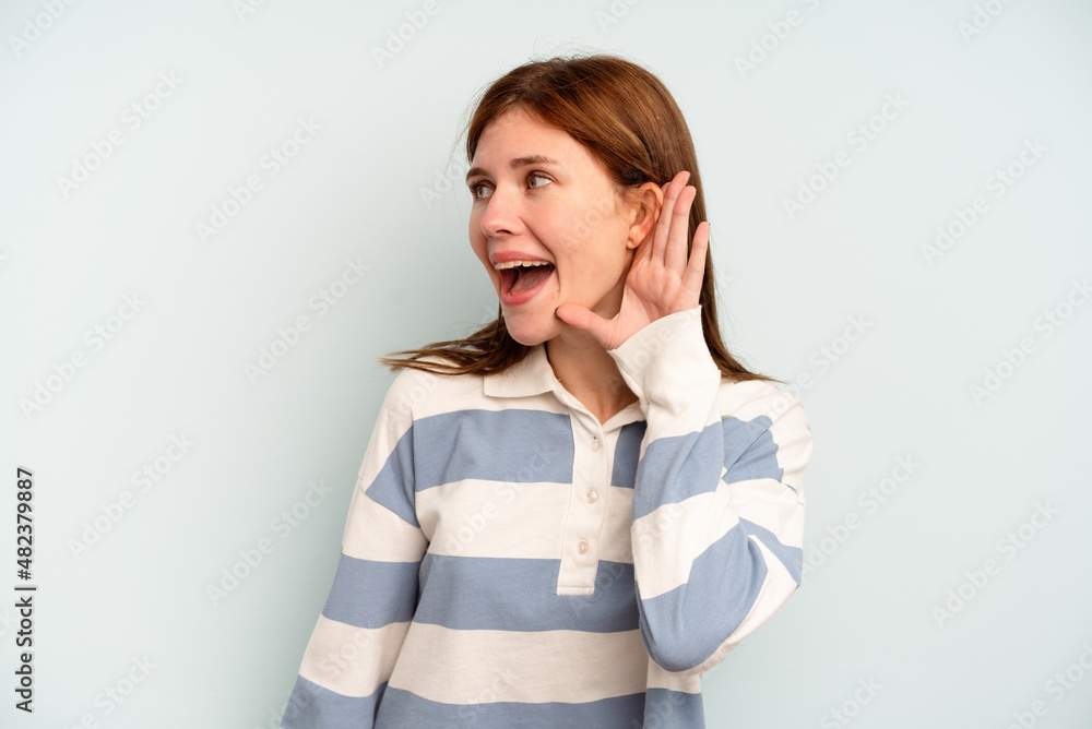 Young English woman isolated on blue background trying to listening a gossip. Young English woman isolated on blue background trying to listening a gossip.