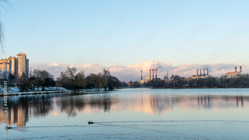 Fototapeta premium Smoking chimneys of a thermal power plant against a winter cloudy sky. Ecological problems concept. Space for text.