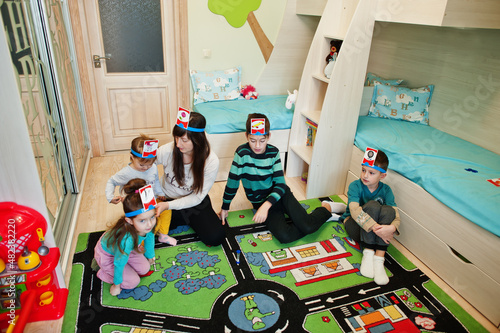 Happy family with four kids playing game guess who while having fun at home. photo