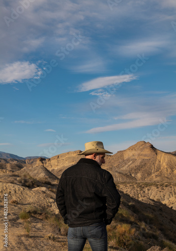 Adult man in cowboy hat standing against mountains in Tabernas desert. Almeria, Spain © WeeKwong
