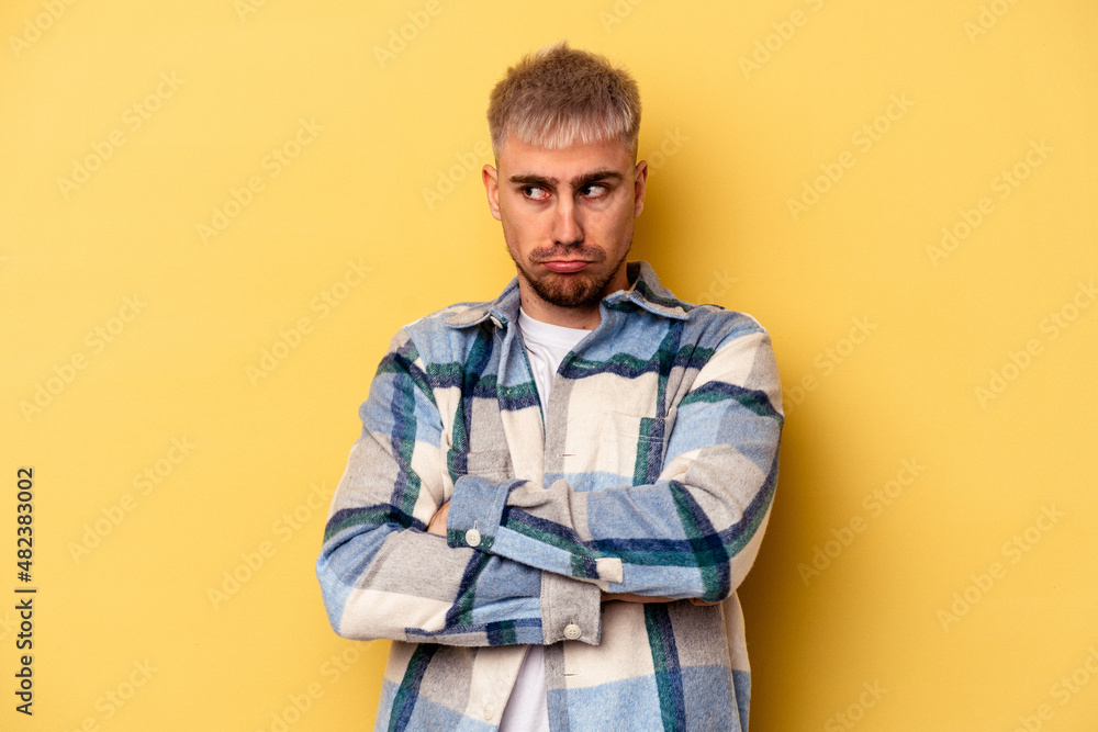 Young caucasian man isolated on yellow background tired of a repetitive task. Young caucasian man isolated on yellow background tired of a repetitive task.