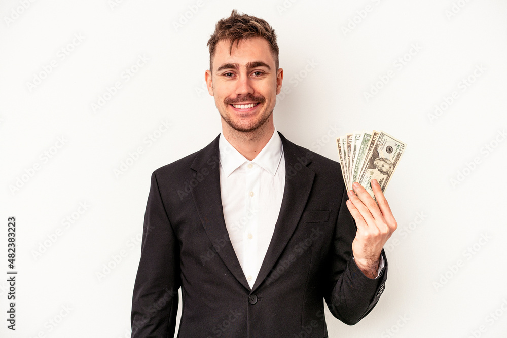Young caucasian business man holding bank notes isolated on white background happy, smiling and cheerful. Young caucasian business man holding bank notes isolated on white background happy, smiling and cheerful.