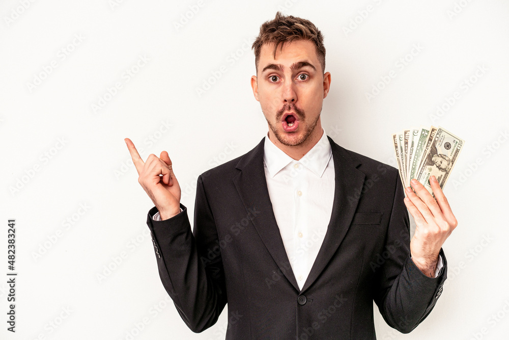 Young caucasian business man holding bank notes isolated on white background pointing to the side Young caucasian business man holding bank notes isolated on white background pointing to the side