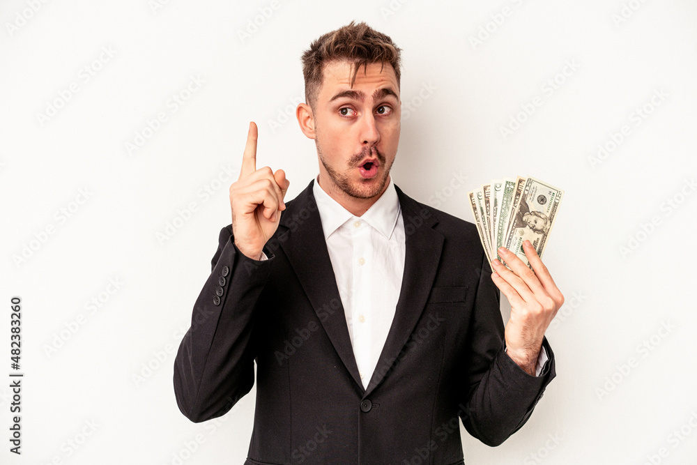 Young caucasian business man holding bank notes isolated on white background having an idea, inspiration concept. Young caucasian business man holding bank notes isolated on white background having an idea, inspiration concept.